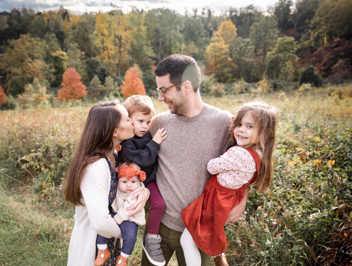 Mother kisses son on cheek during lifestyle family picture taking in Baltimiore County, Maryland