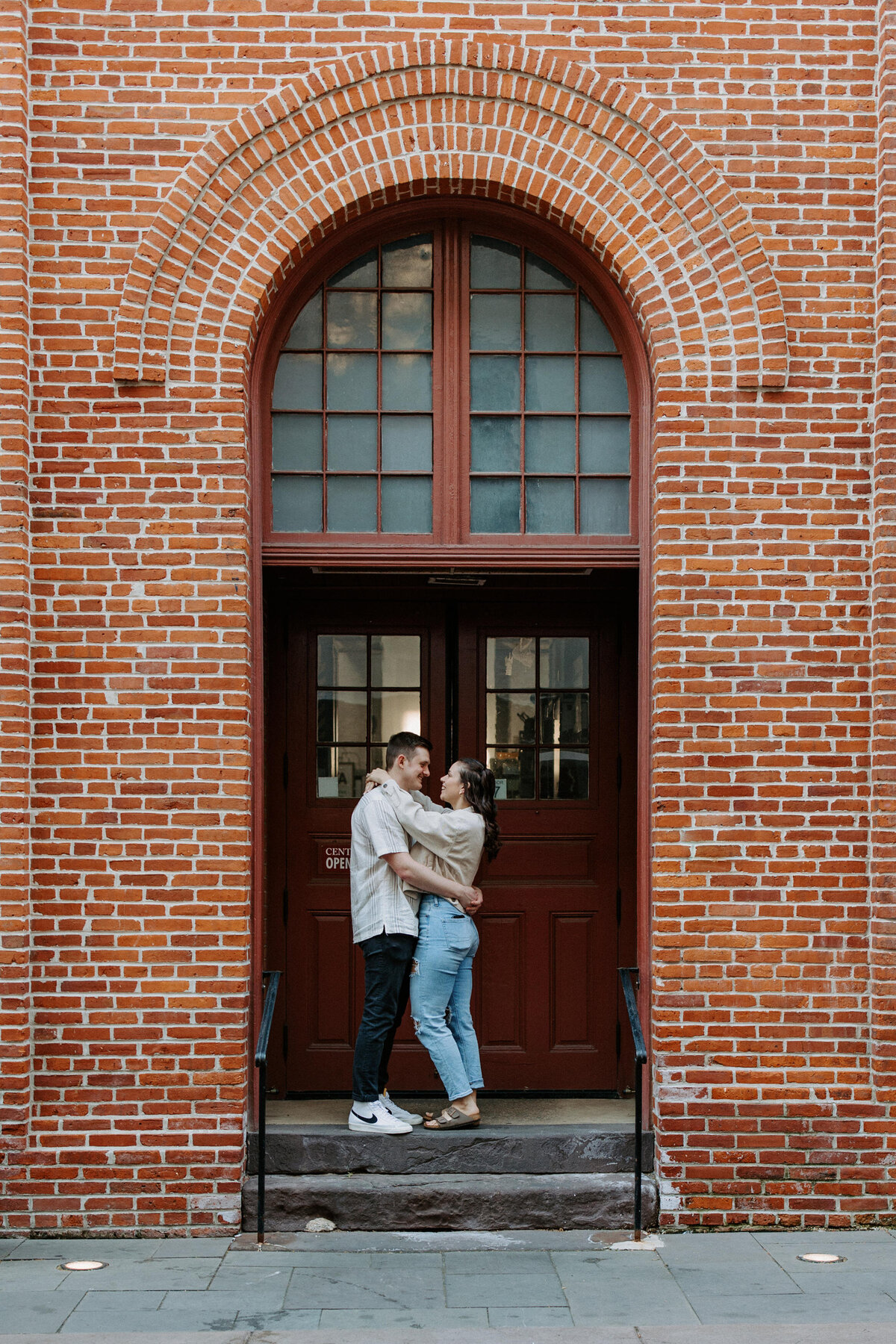 couple with their arms around each other while they stand in an arched doorway