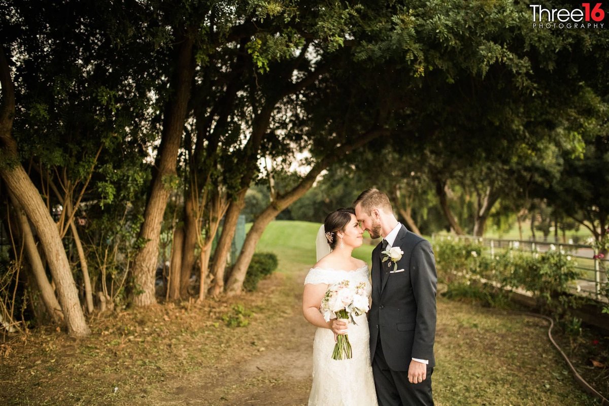 Tender moment between newly married couple as they walk through the trees