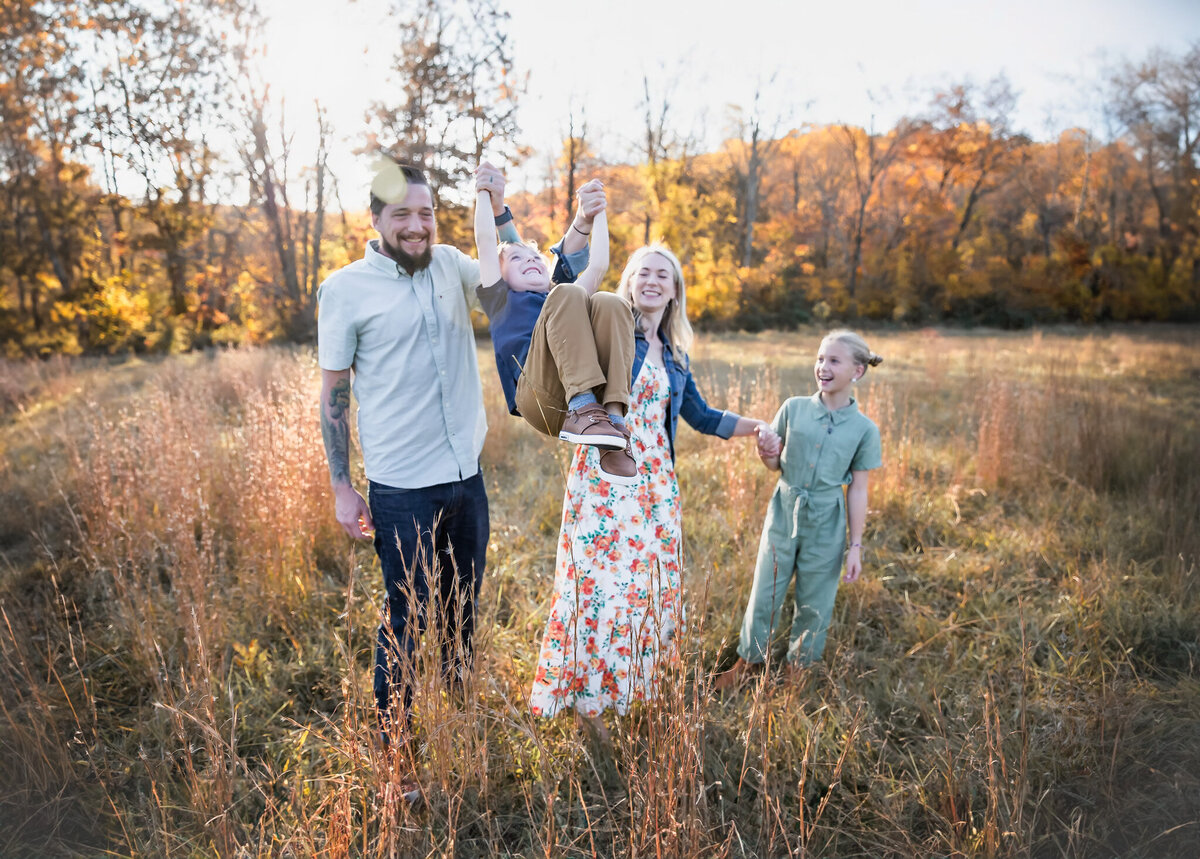 Mom and Dad swing their son while photographer takes lifestyle photos in Baltimore County, Maryland