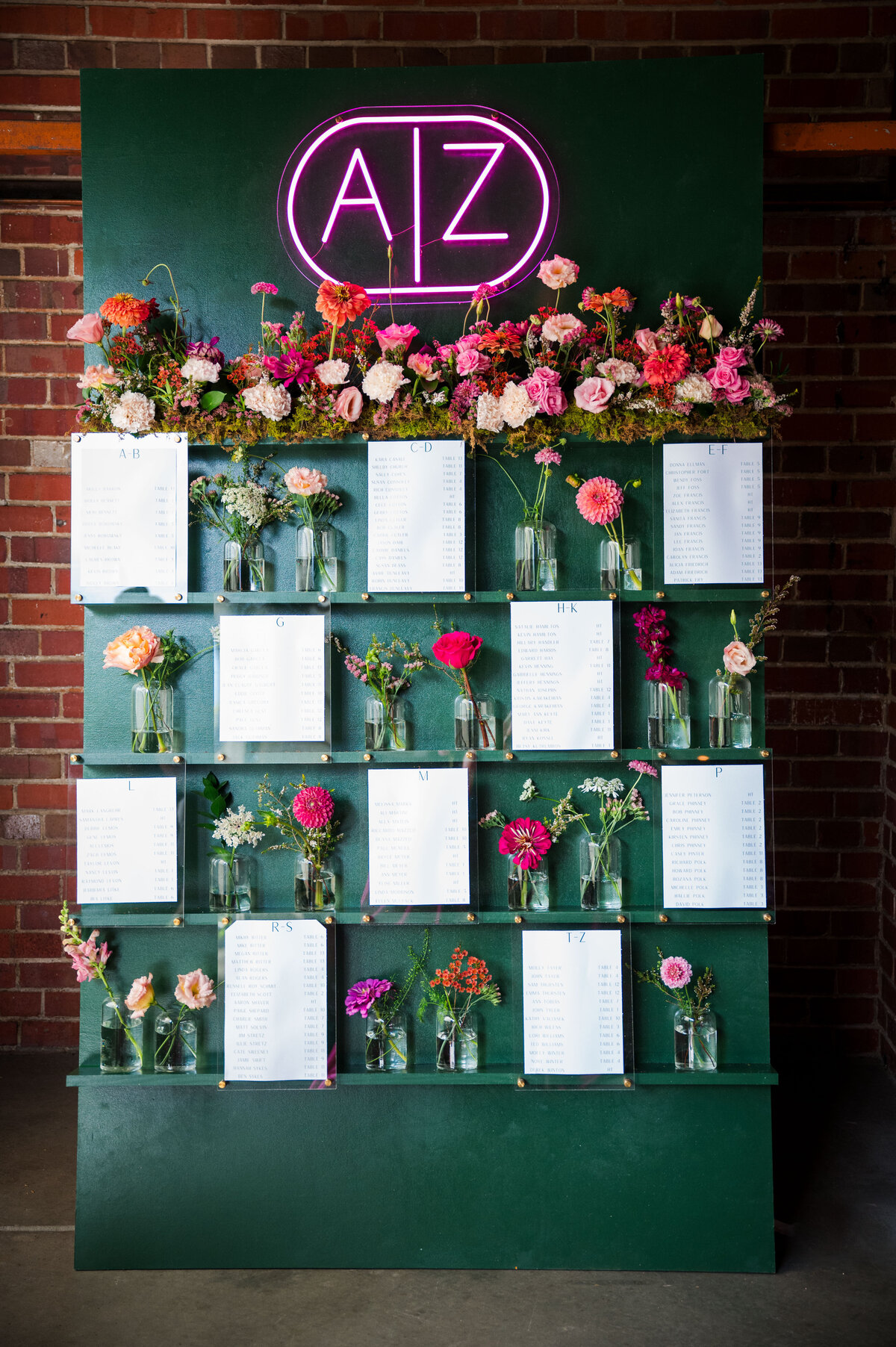 A unique seating chart is adorned with various colored wild flowers and a neon letter sign reading "A|Z."