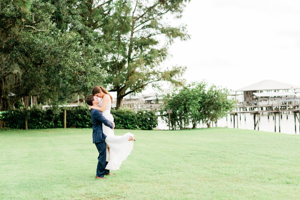 Groom holding bride up on grass in Alabama
