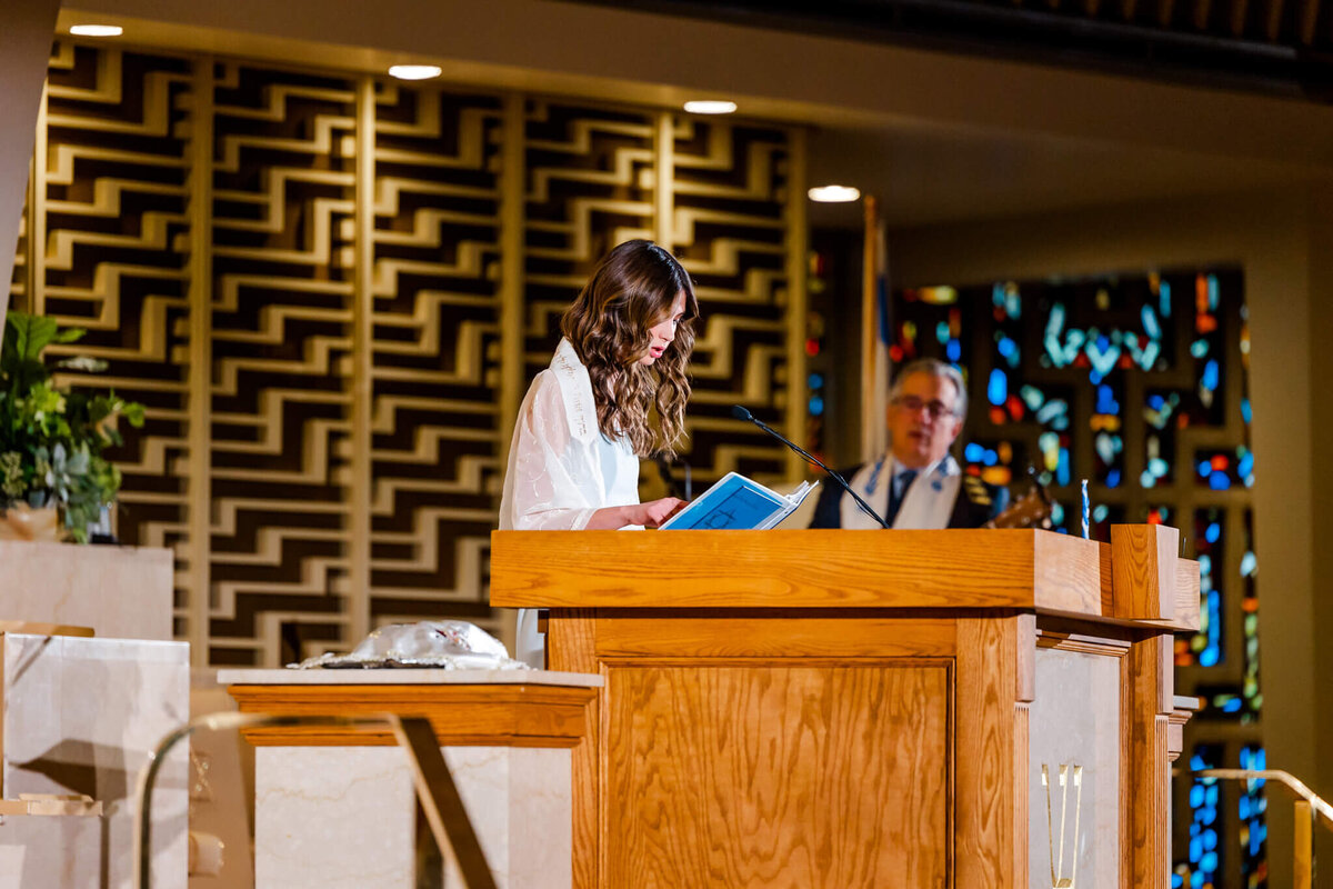 A teen girl reads into the microphone on the bimah