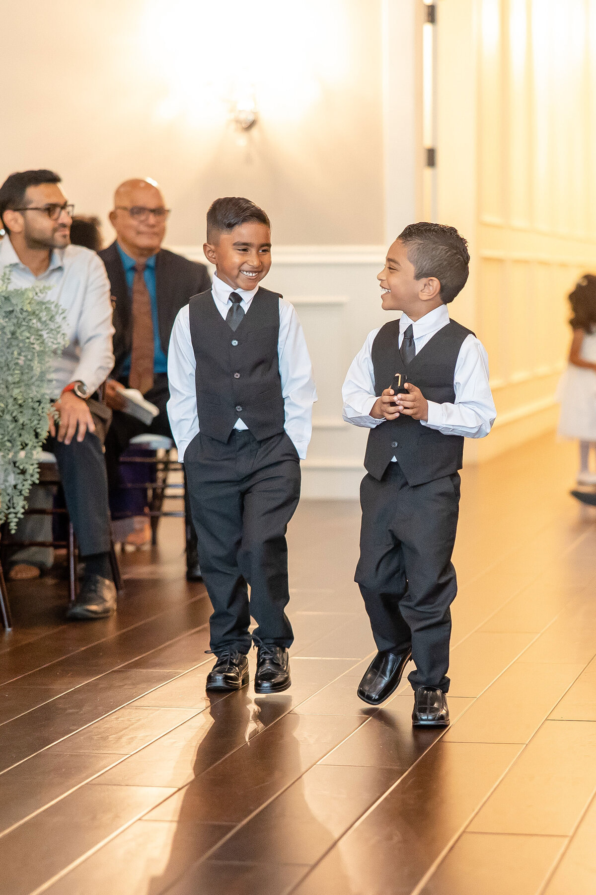 two young boys laugh together as they walk down the aisle at Aubrey Mansion wedding