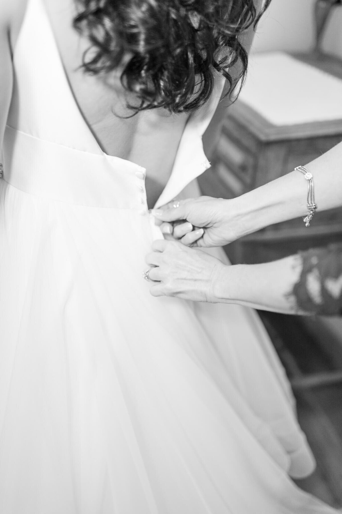 black and white close up photo of hands zipping a brides dress by arkansas wedding photographer