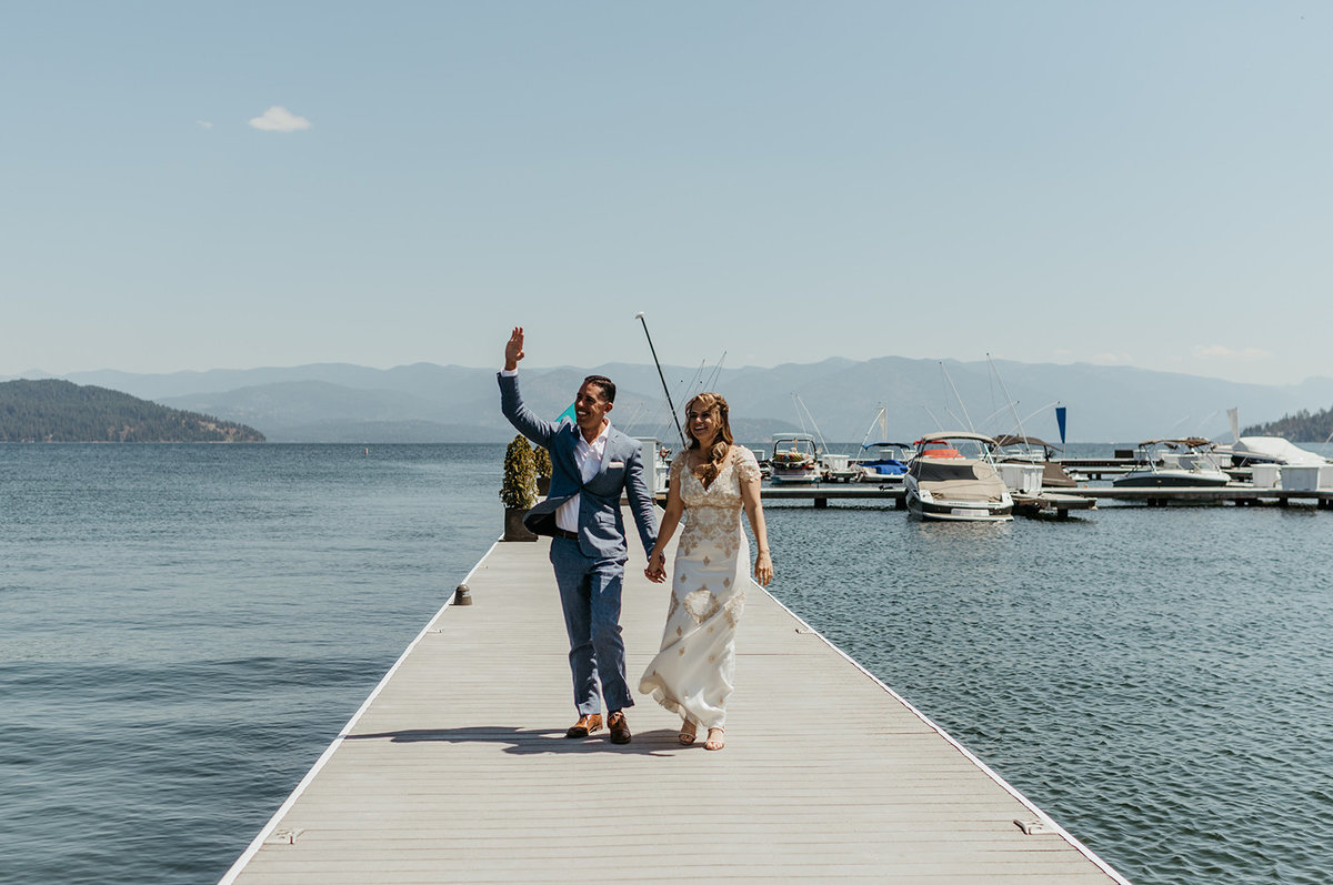Couer d'Alene bride & groom waving from waterfront