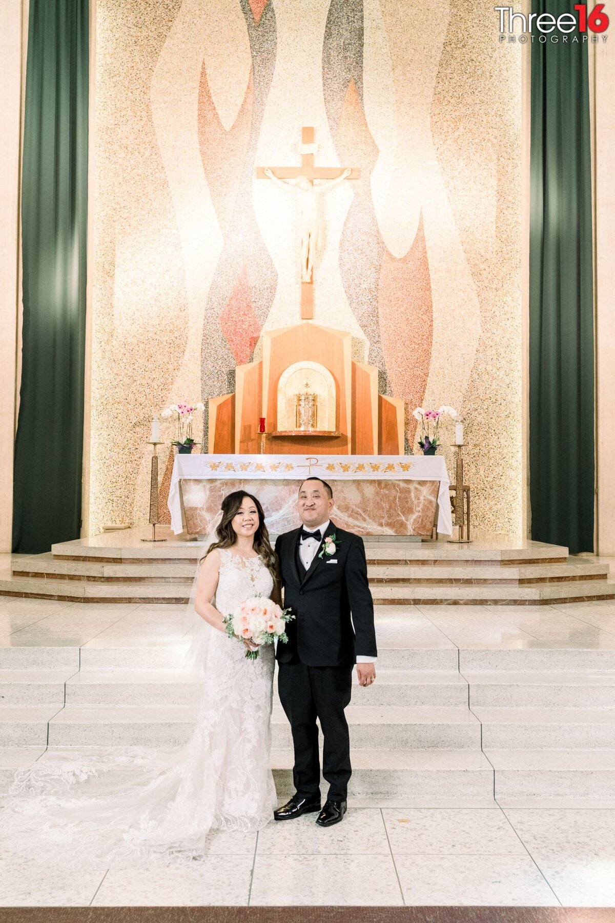 Bride and Groom pose for the wedding photographer in front of the altar inside the church