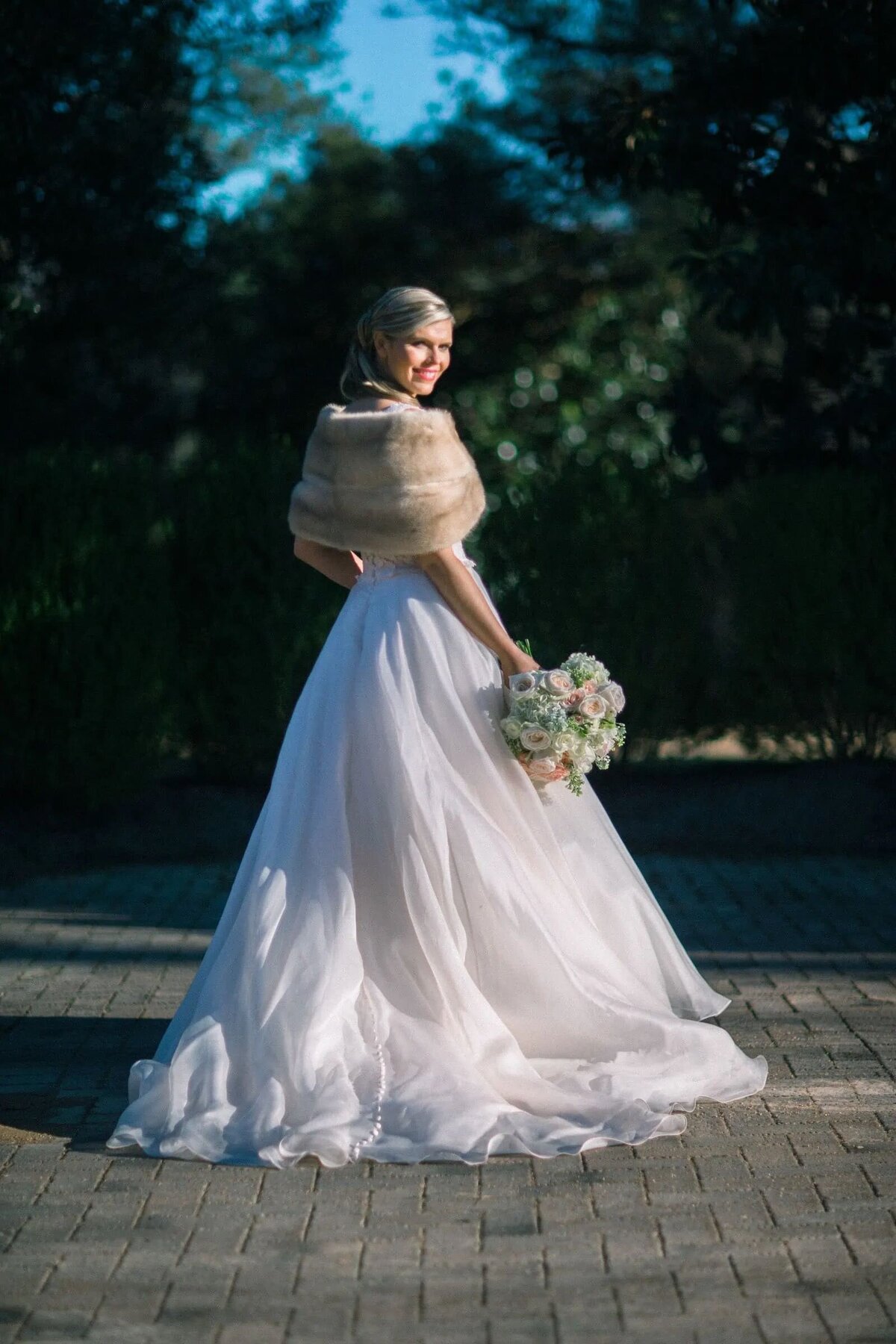 A bride with a fur scarf over her shoulders looking back