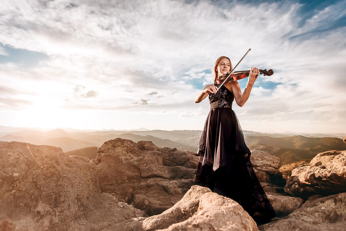 girl with violin on a mountain top at sunset