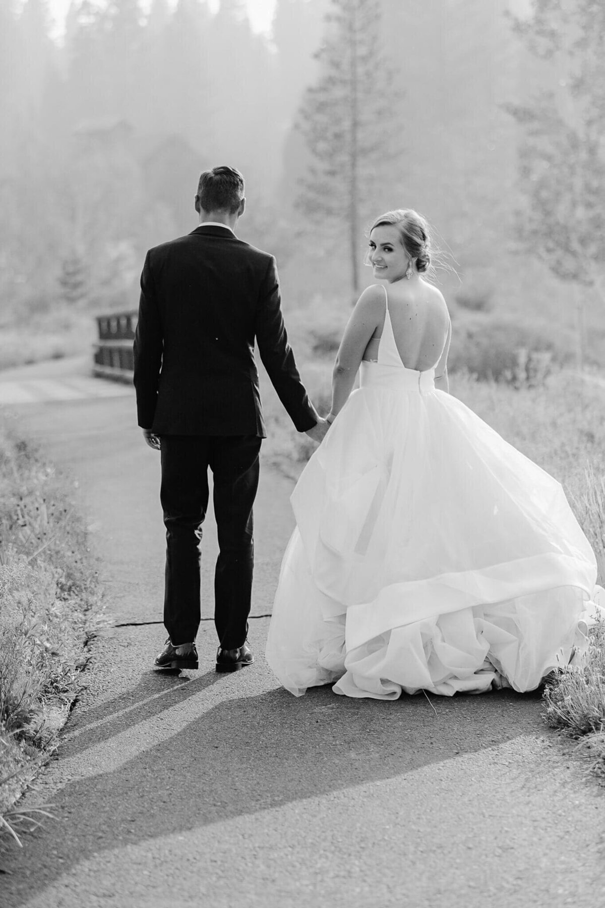 Newlyweds walking with bride looking over shoulder during wedding at Martis camp