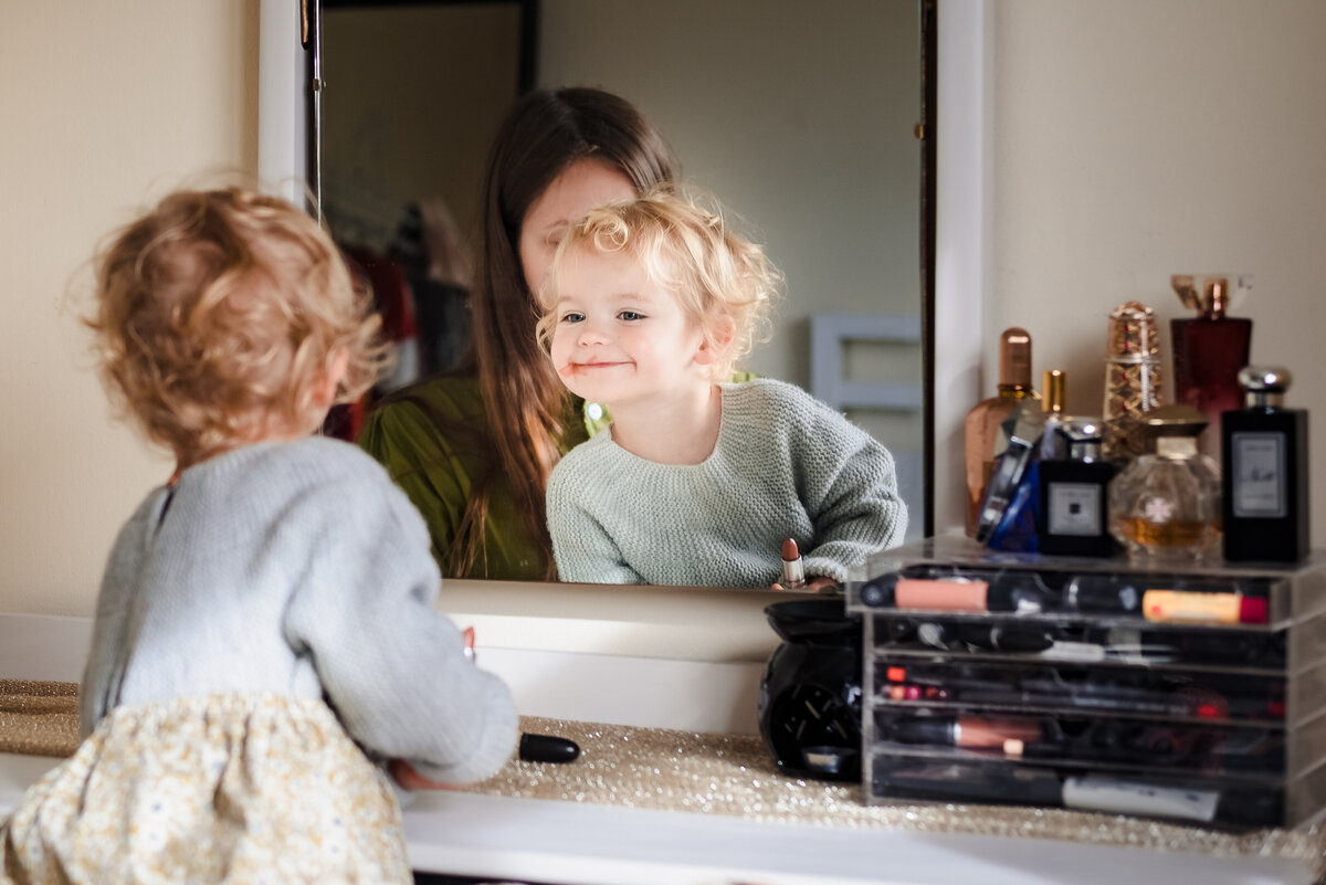little girl checking out her makeup in mirror during family photoshoot