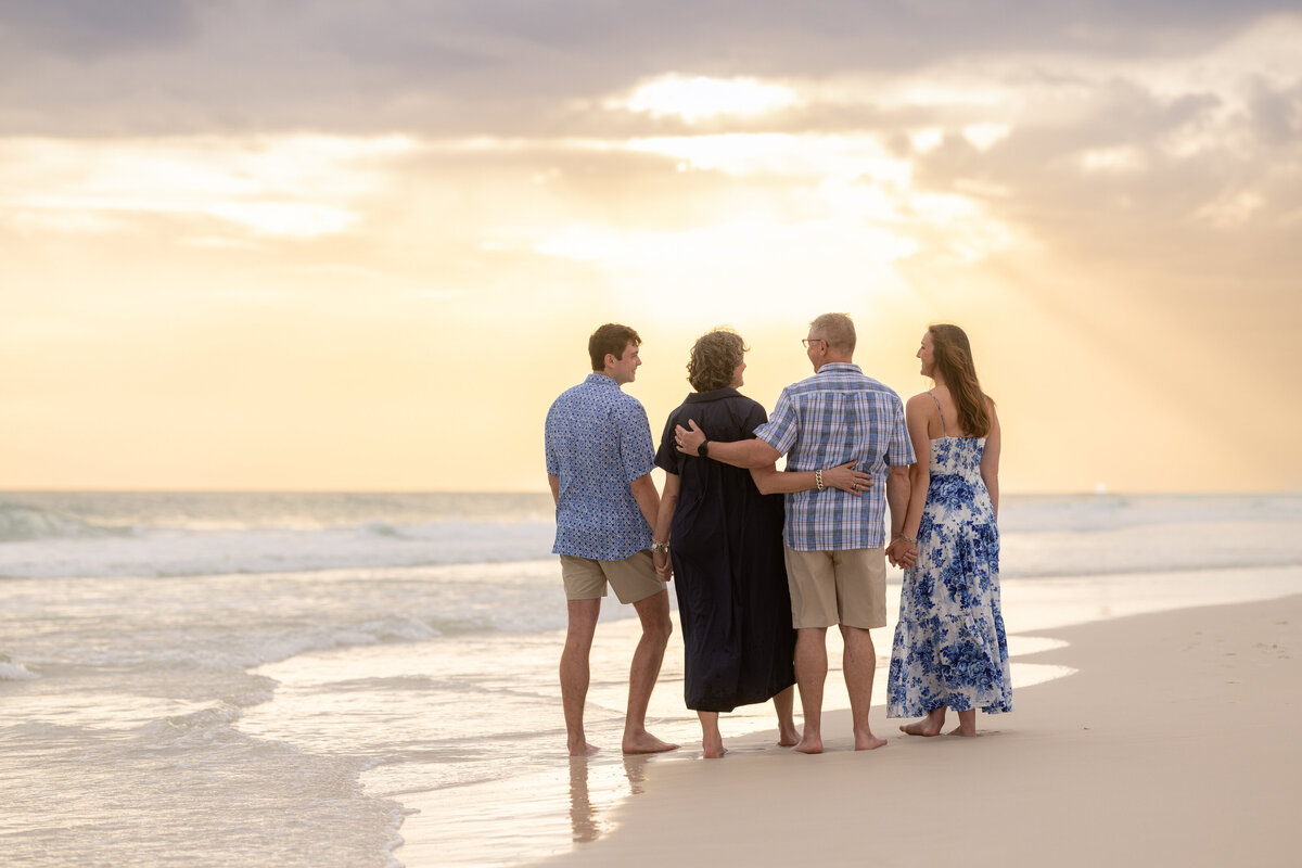 Parents with their older children, facing the sunset at Watersound Beach Club in the Florida Panhandle.