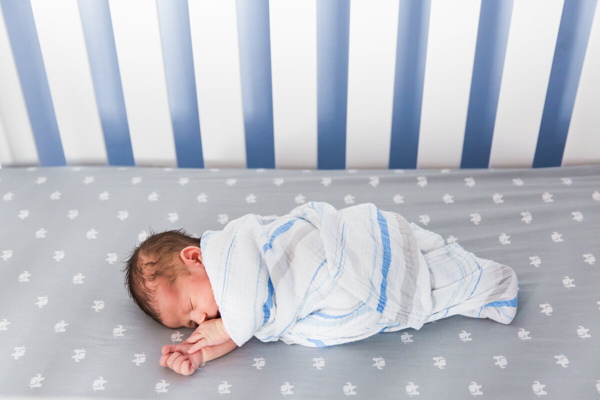 newborn baby sleeping in crib  in lifestyle photography session