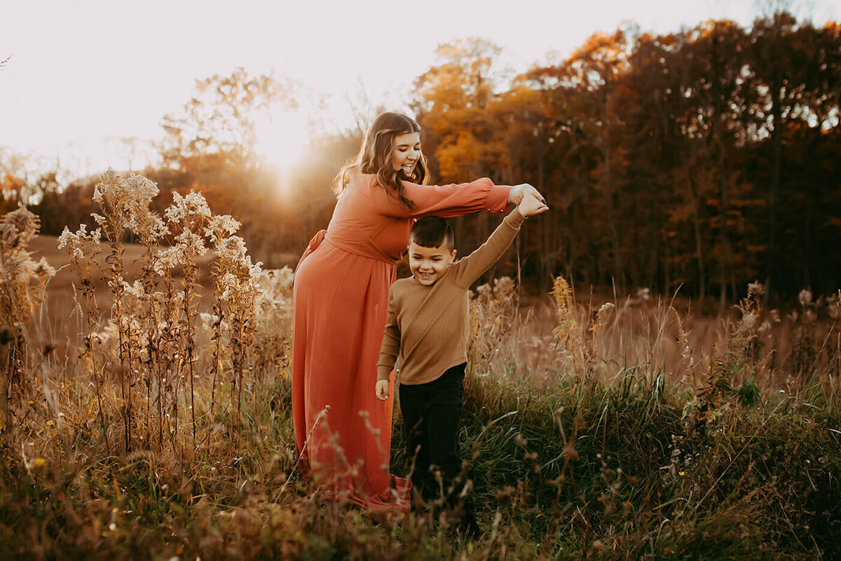a mother and son dancing in a field in october