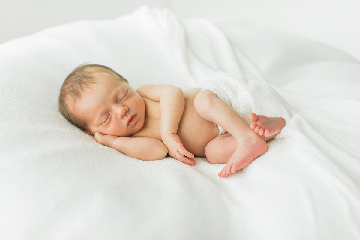 newborn baby is positioned on side with hand under cheek for heirloom portrait