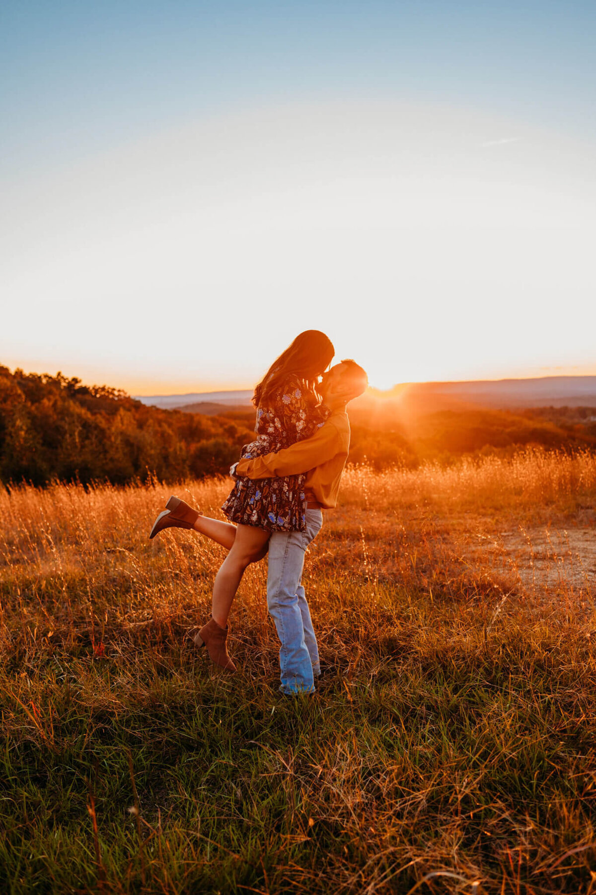 photo of a man picking up his fiancee romantically while in a field