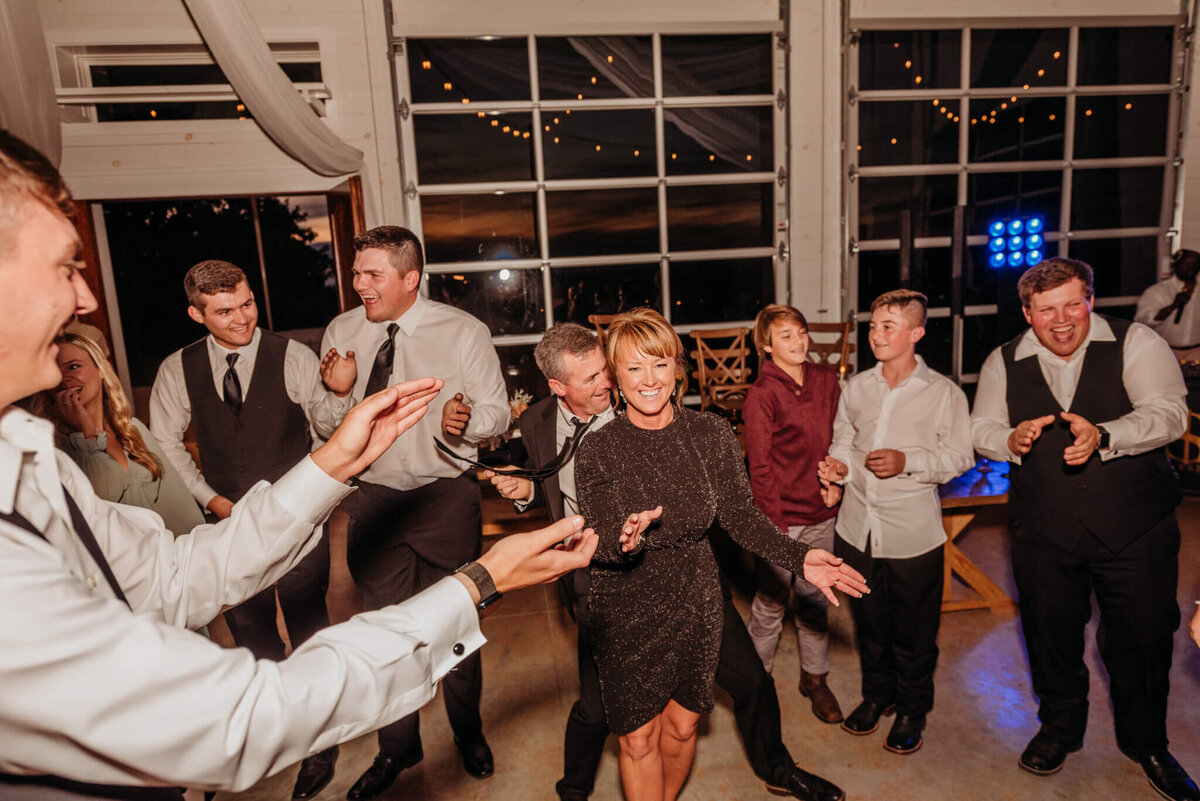 photo of wedding guests dancing inside of a glass venue