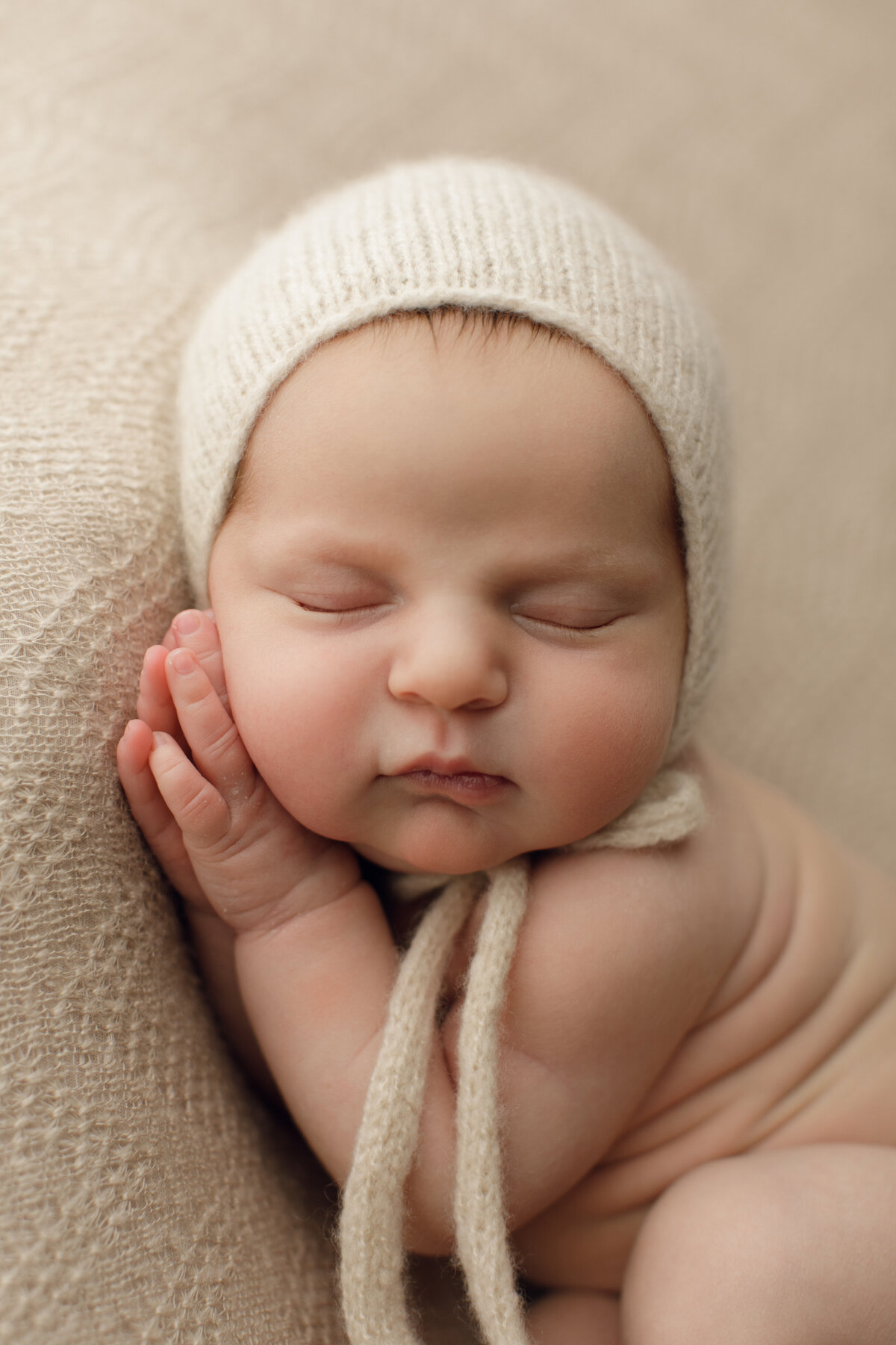 sleeping newborn baby with white bonnet