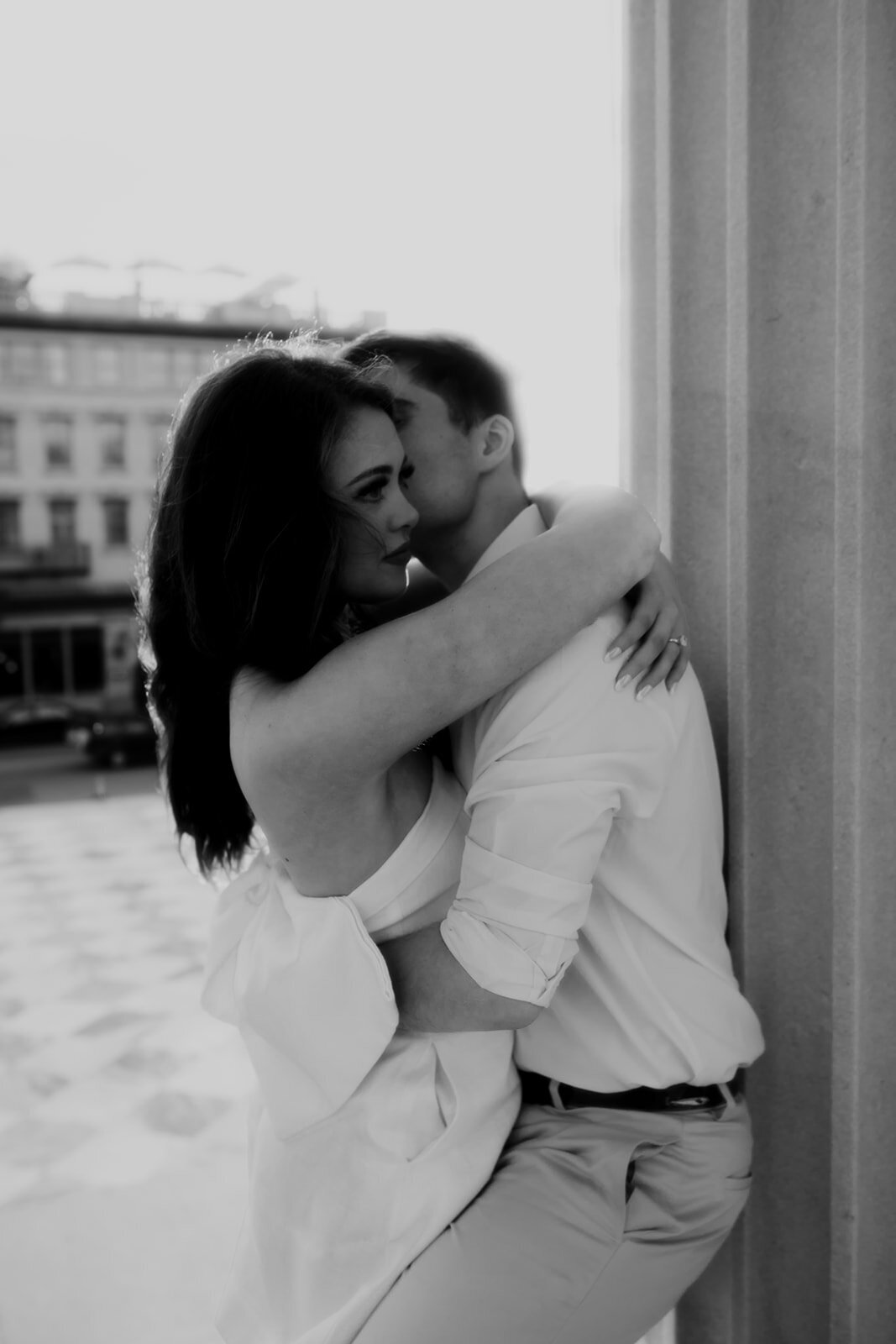 Nostalgic black and white photo of Charleston engagament photo session. Man leaning on column and holds on to woman.