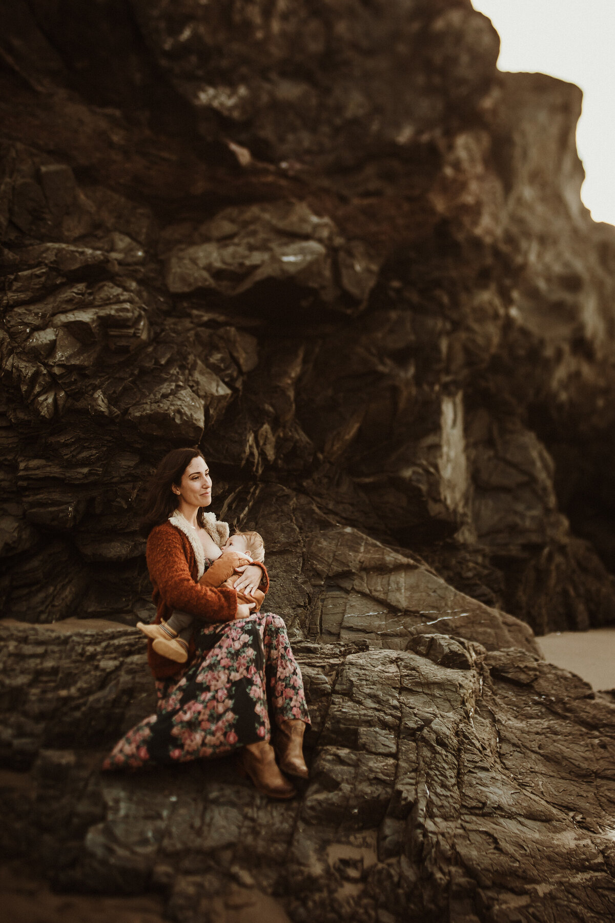 Motherhood portrait breastfeeding on rocky coastline