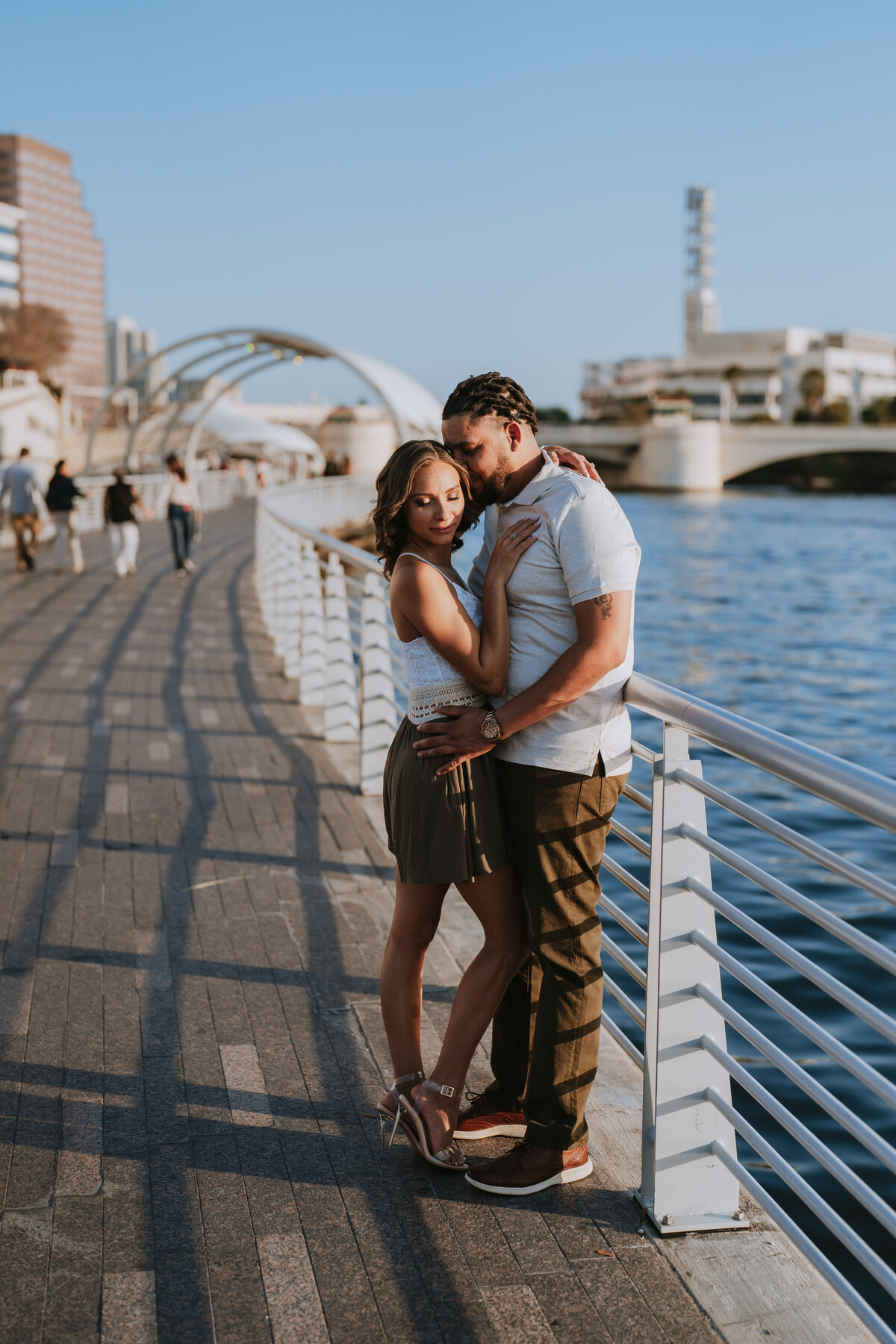 couple snuggled up on the tampa riverwalk for engagement photos