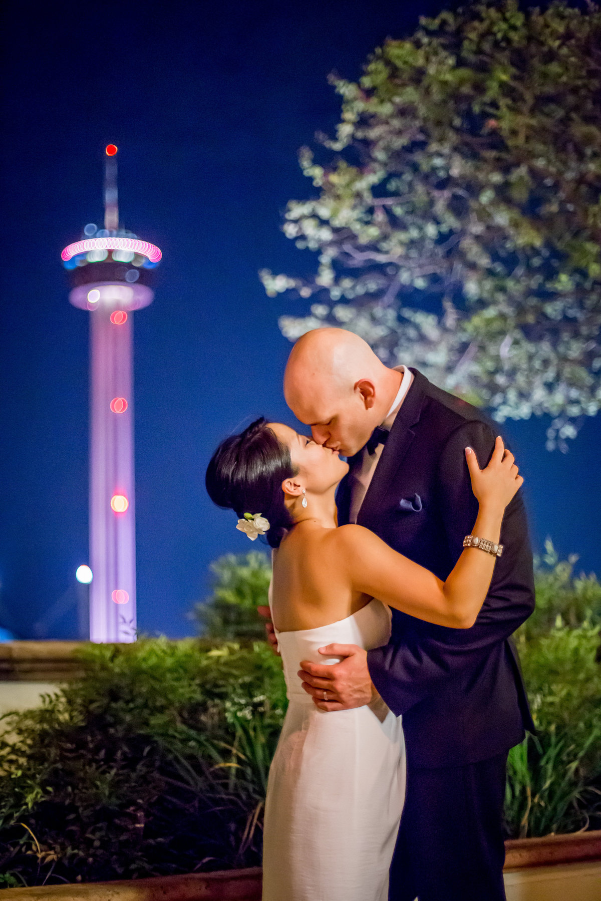 Bride and Groom kissing with Tower of the Americas in back ground at Hilton Palacio del Rio wedding venue