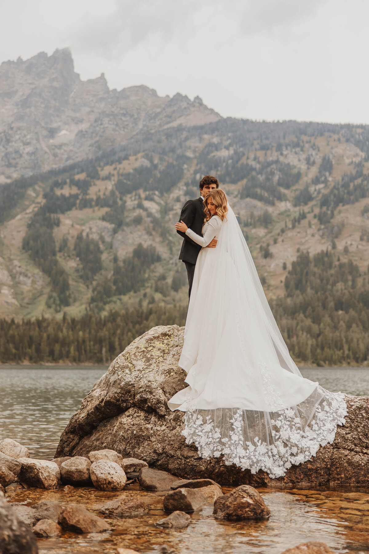 bride and groom kissing on large rock
