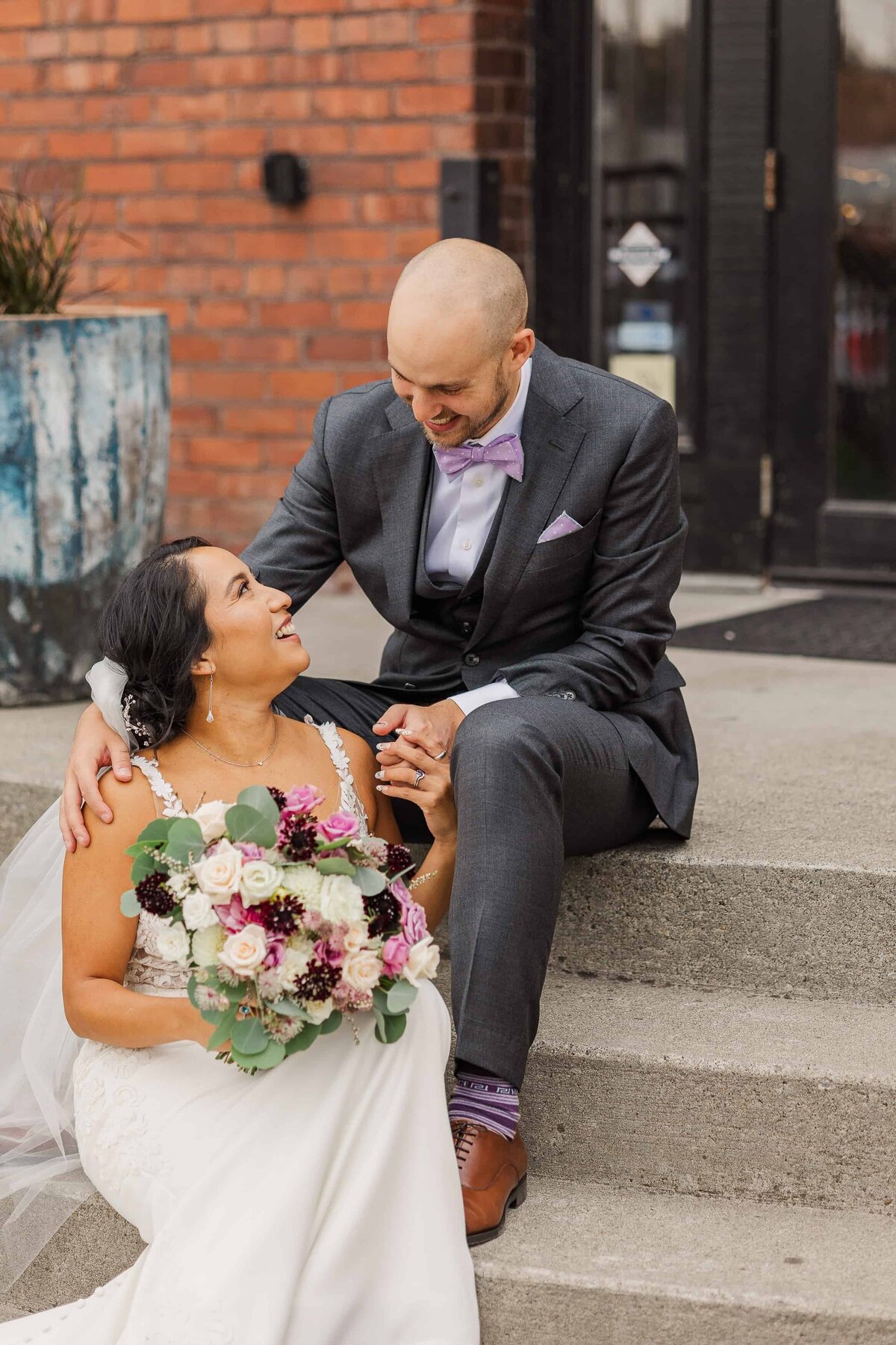 Bride and groom, sitting in front of the realm, Tacoma venue, steps, smiling at each other