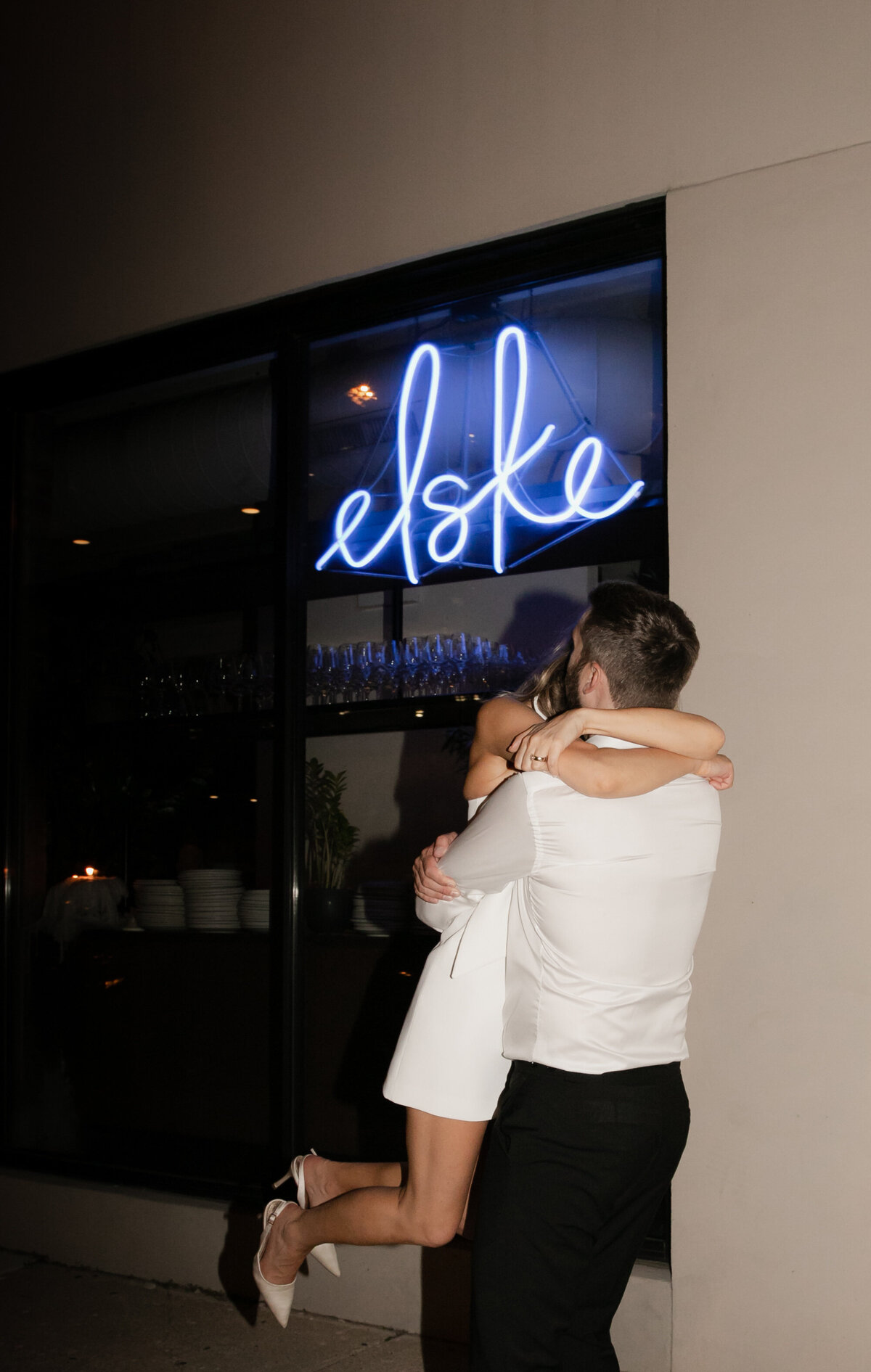 Groom at Elske Restaurant wedding reception lifts bride off the floor in an embrace.