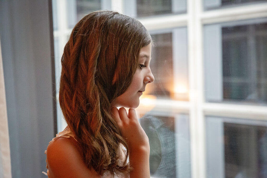 Brides daughter looks out hotel window