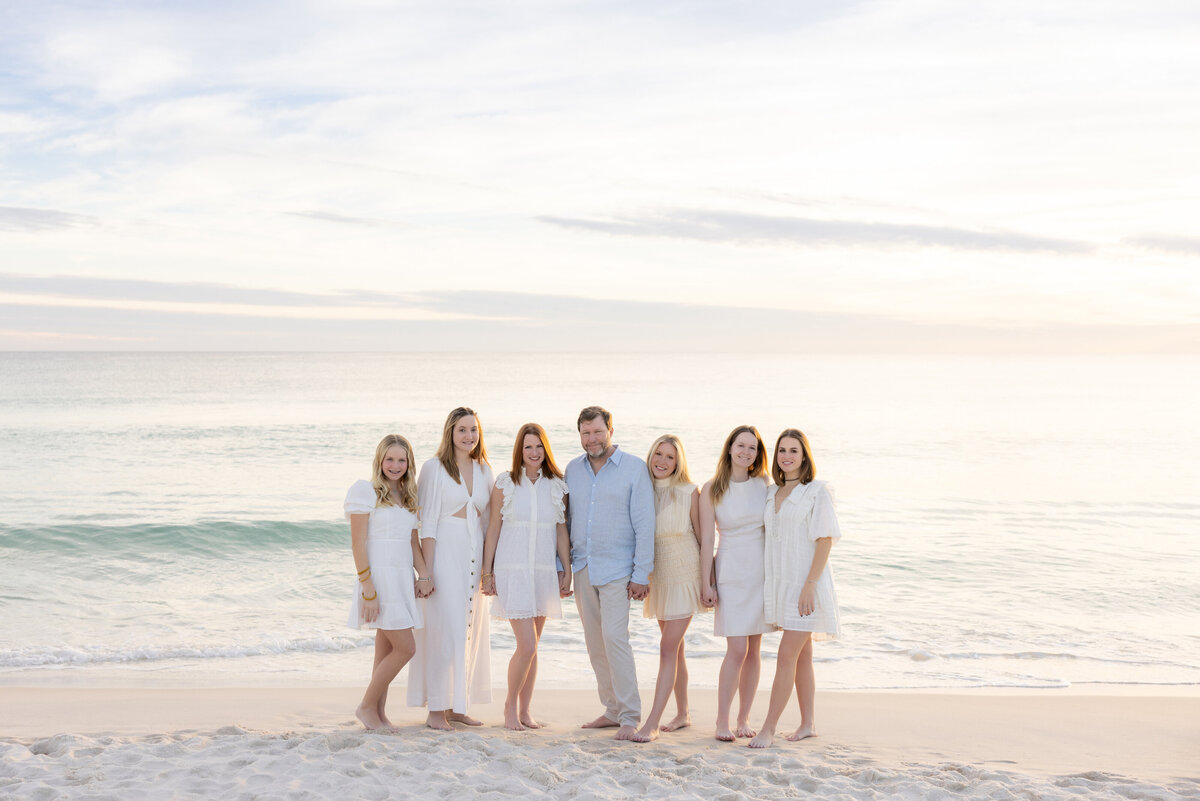 A family with their arms around each other smiling at the beach