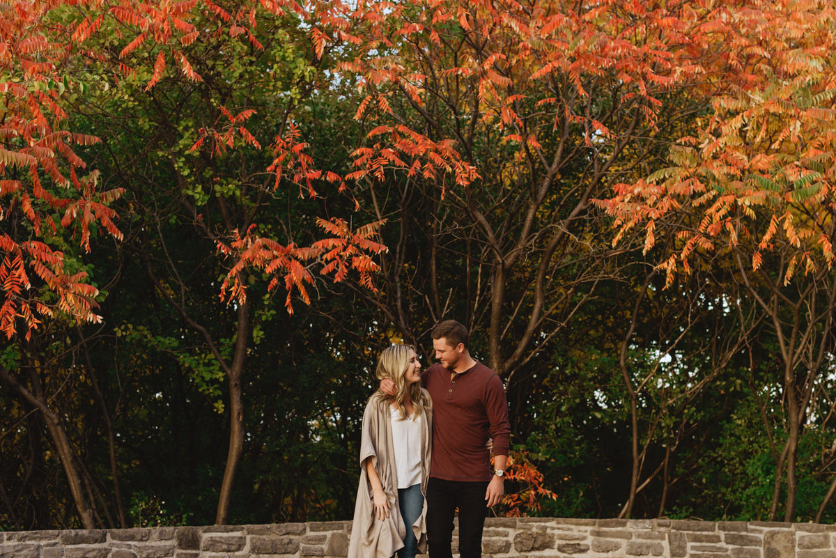 engaged couple walking in the fall trees