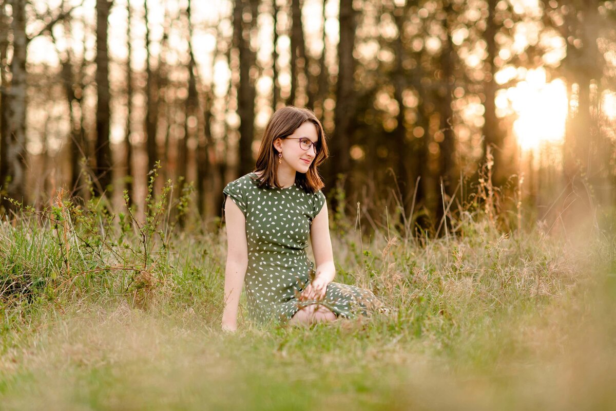 monroe senior sits in a field of tall grass dressed in green