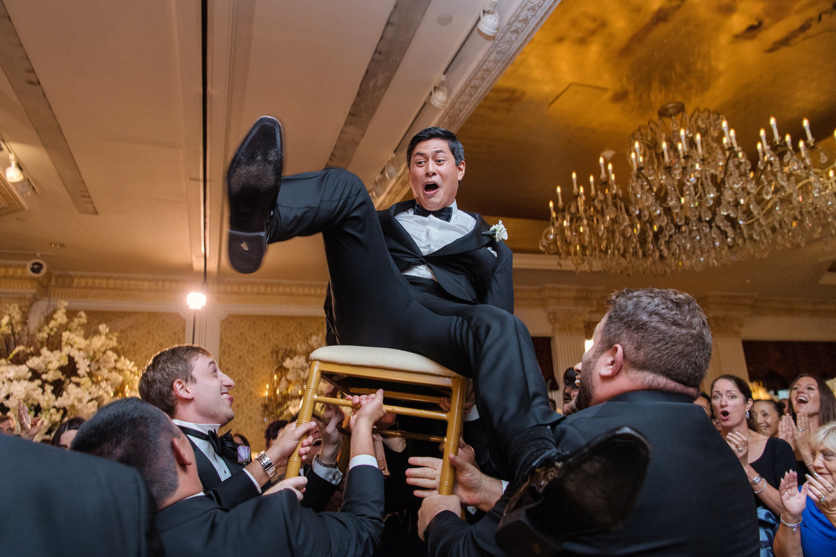 photo of groom during the chair dance during wedding reception at The Garden City Hotel