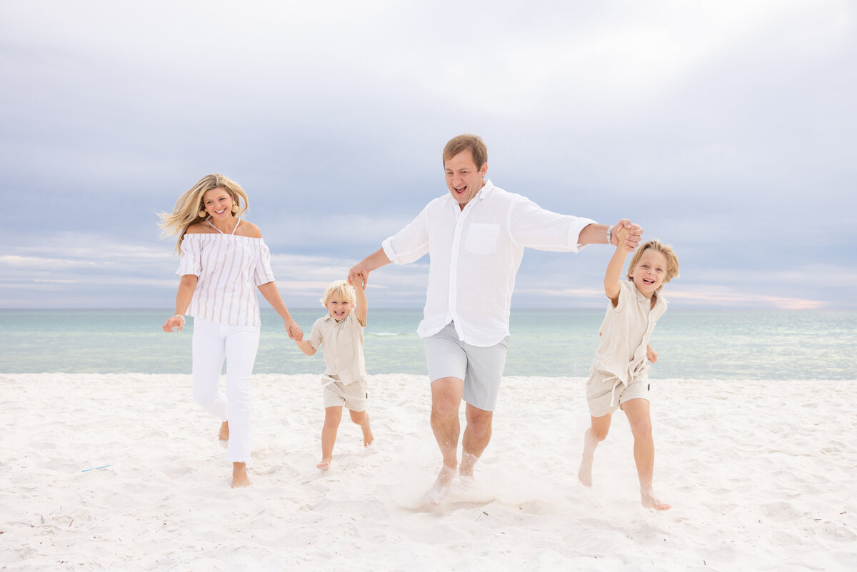 Parents and their kids holding hands and running at the beach