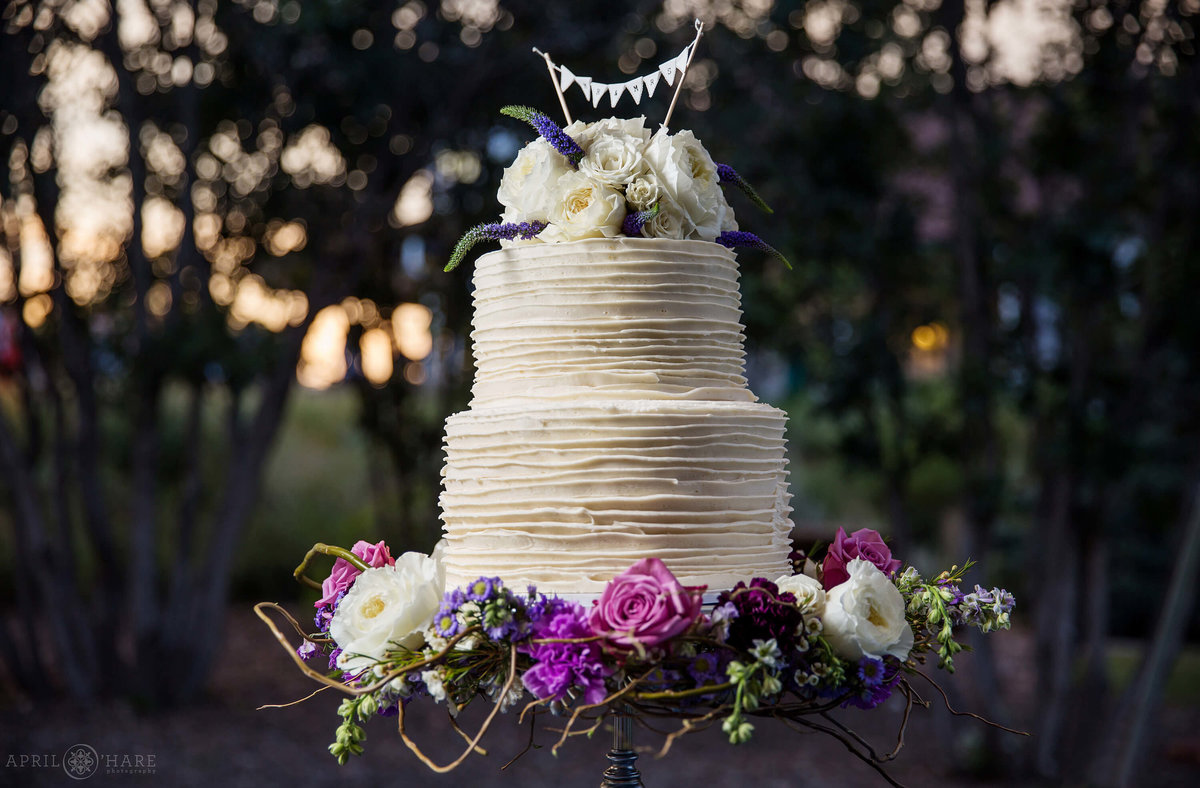 Stunning photo of a white wedding cake at sunset Chatfield Farms in Colorado