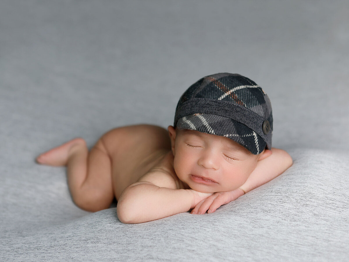 Newborn-photography-session-newborn-boy-with-grey-hat-sleeping-on-belly-,-photo-taken-by-janina-botha-photographer-in-Oakville-Ontario