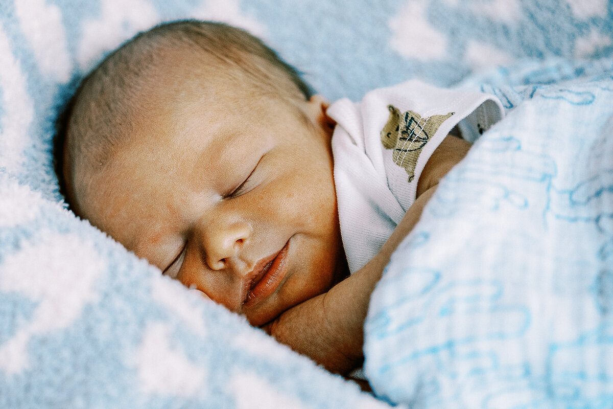 smiling baby swaddled in blue