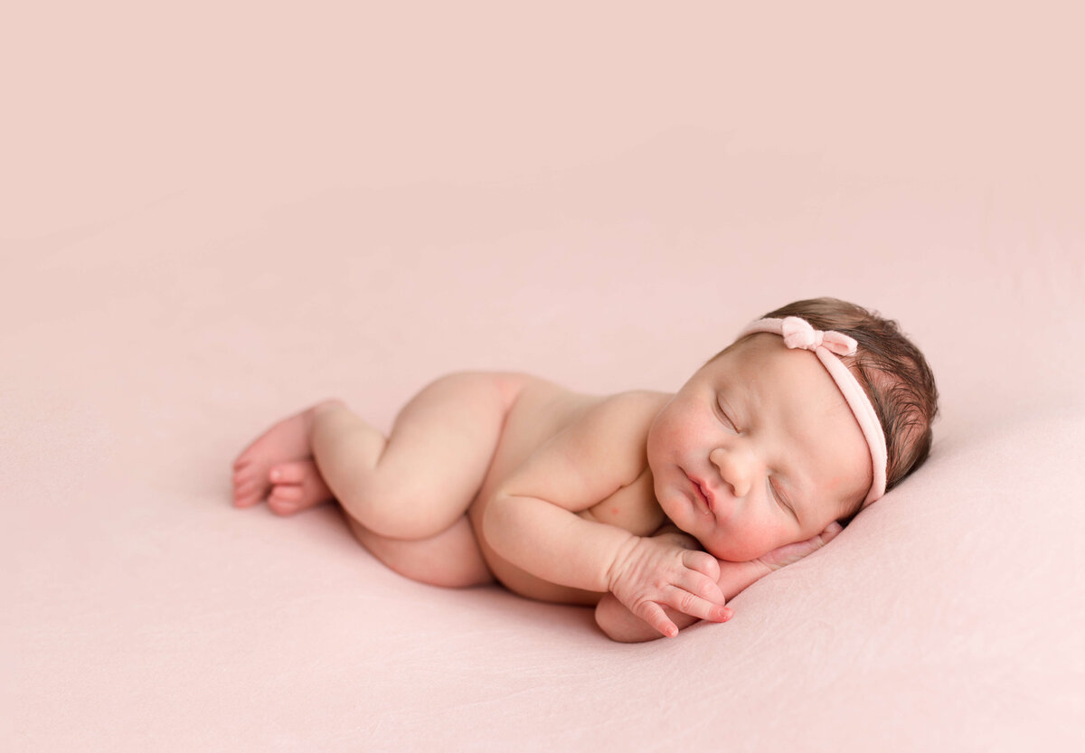 baby girl lying on side on pink fabric