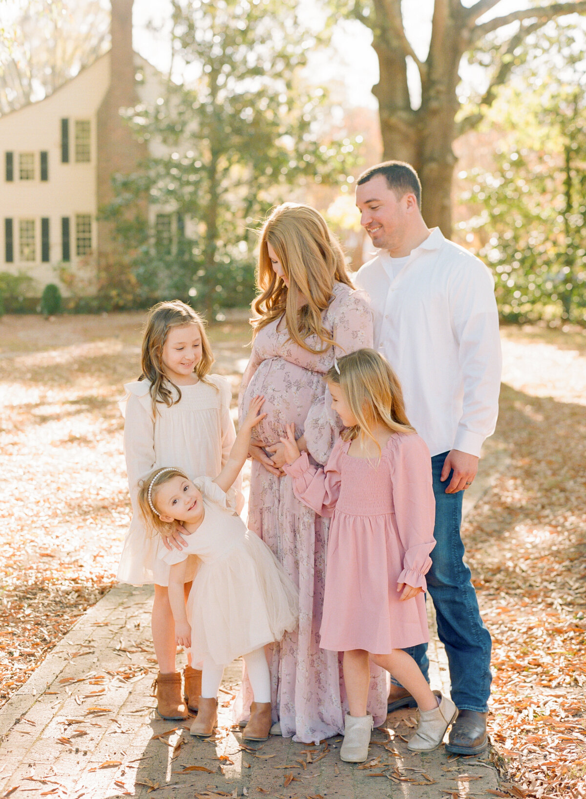 Family laughing while touching mom's pregnant belly during a Wake Forest maternity session. Photographed by Raleigh maternity photograph A.J. Dunlap Photography.