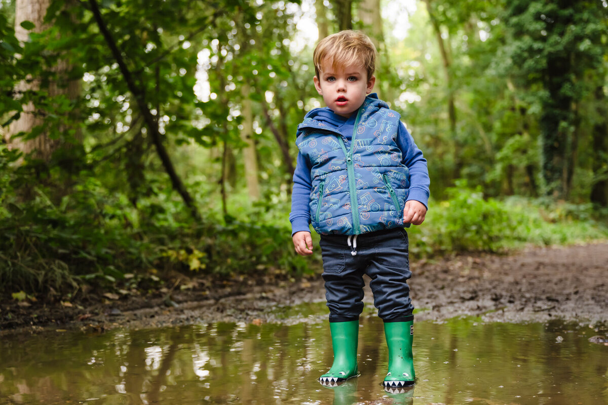 Little boy stood in puddle with his wellies on at barnsdale woods