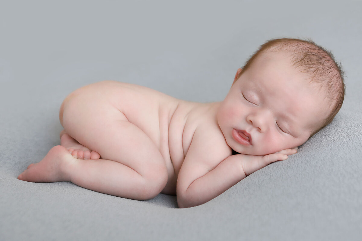 Little-boy-only-8-days-old-sleeping-soundly-for-his-newborn-session-on-a-grey-blanket