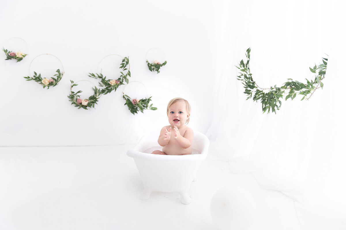 A toddler girl plays in a small bathtub in a studio of a childrens photographer Atlanta