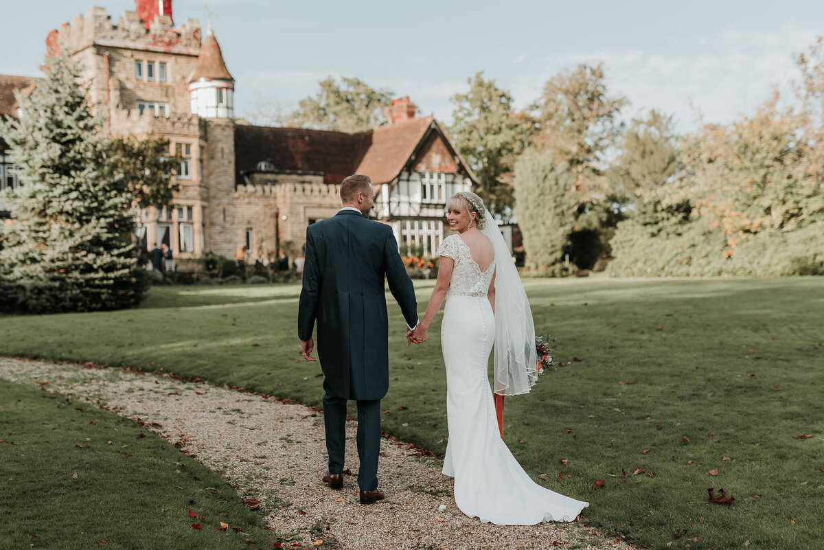 Bride & Groom walking along stone pathway at their joyful autumn wedding at The Ravenswood