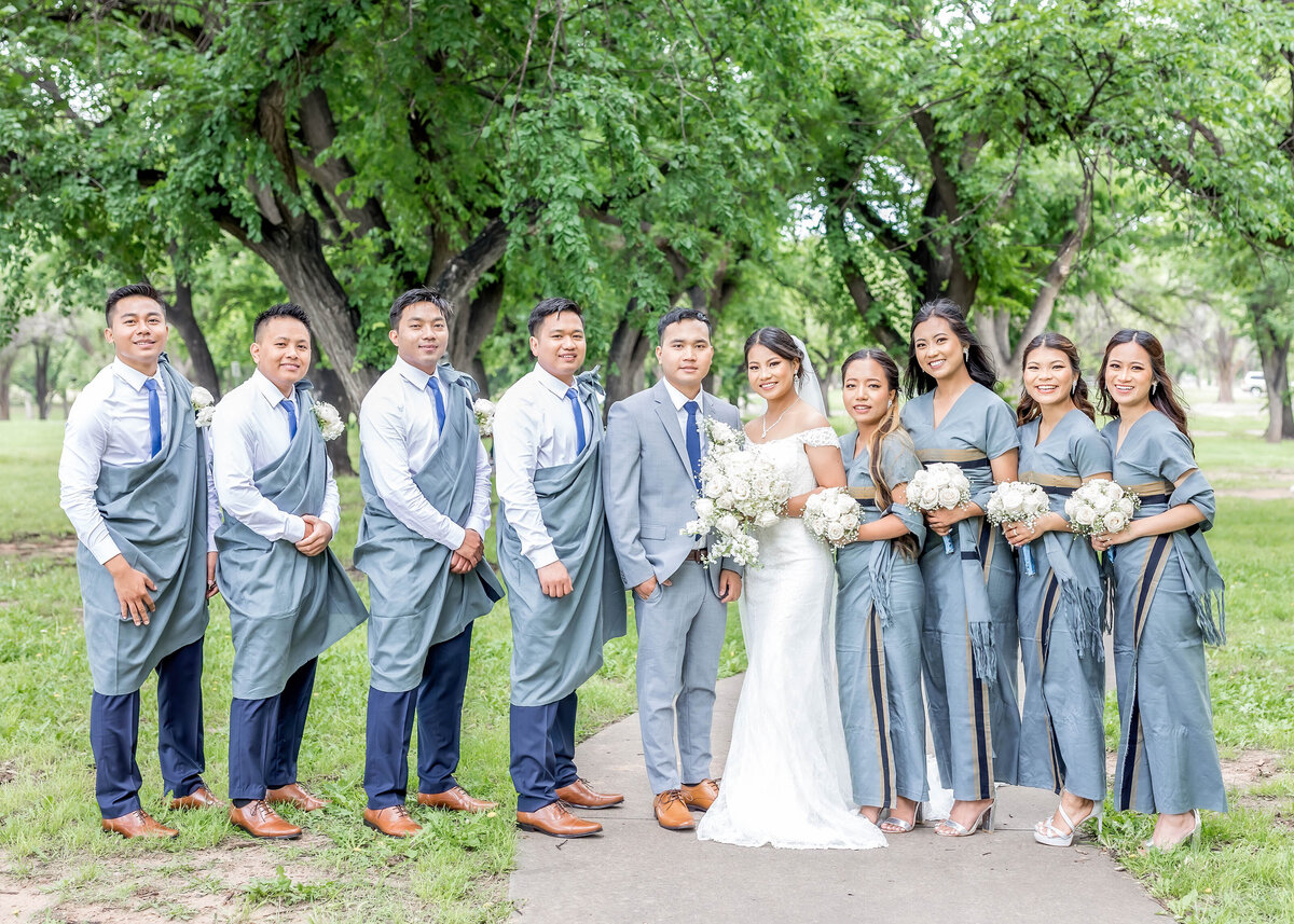 Burmese wedding party at Thompson Memorial Park in Amarillo Texas.  The bridesmaids are holding bouquets and the wedding party is looking at the camera.