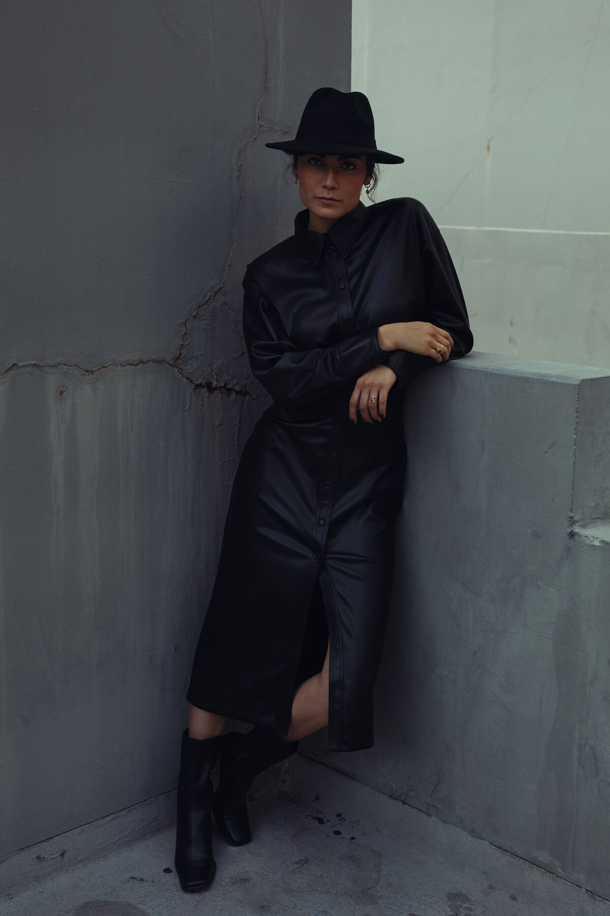 Portrait Photo Of Young Woman In Black Boots And Black Coat Leaning Against a Wall Los Angeles