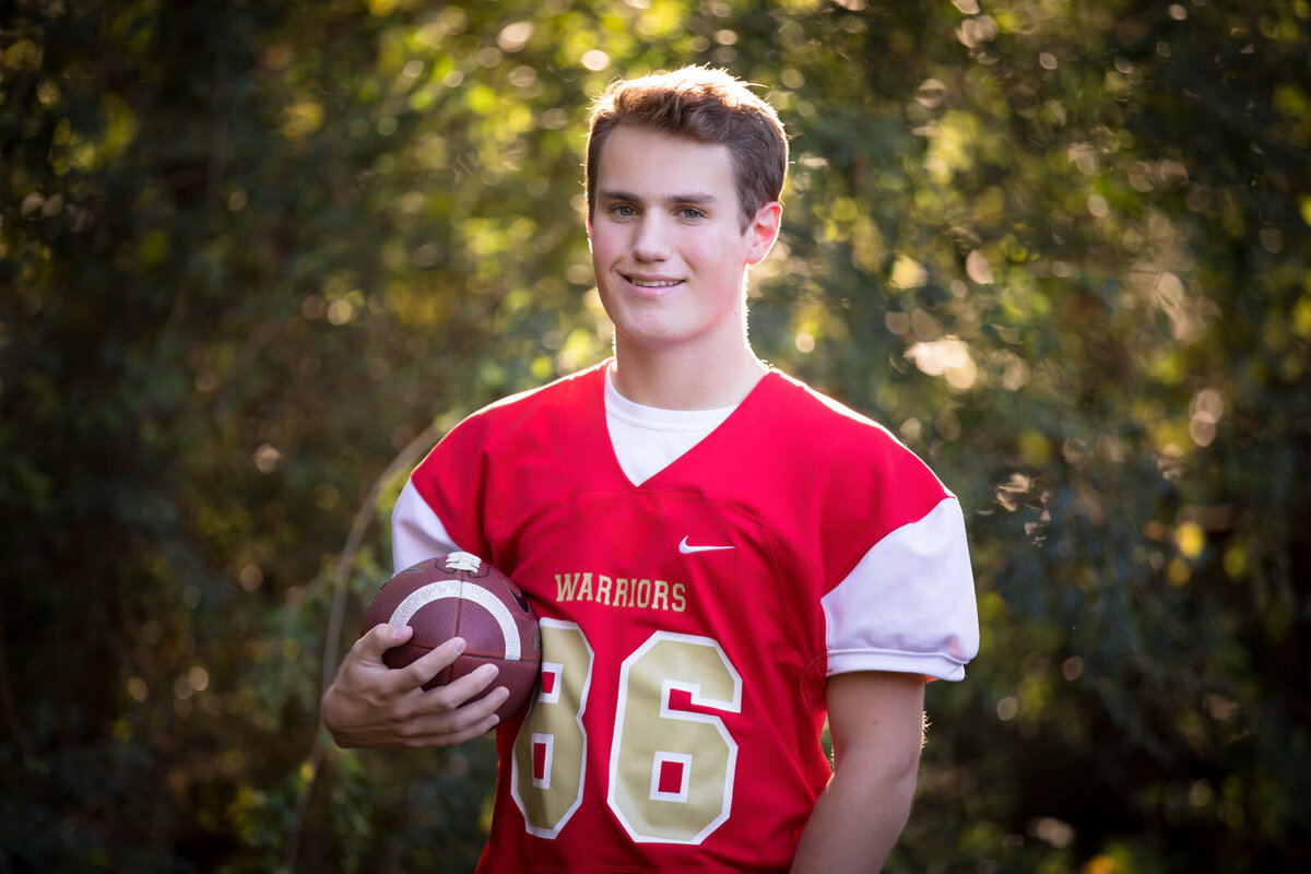 senior-in-red-jersey-holding-football