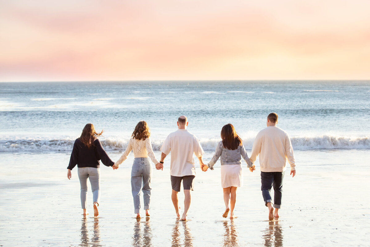 Family of 5 enjoying the sunset and holding hands in Malibu