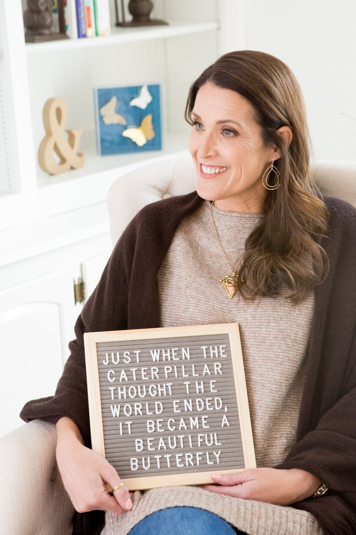 white women in a cardigan holds a letter board sign saying just when the caterillar thought the world ended, it became a butterfly New York branding photographer Milestone Images