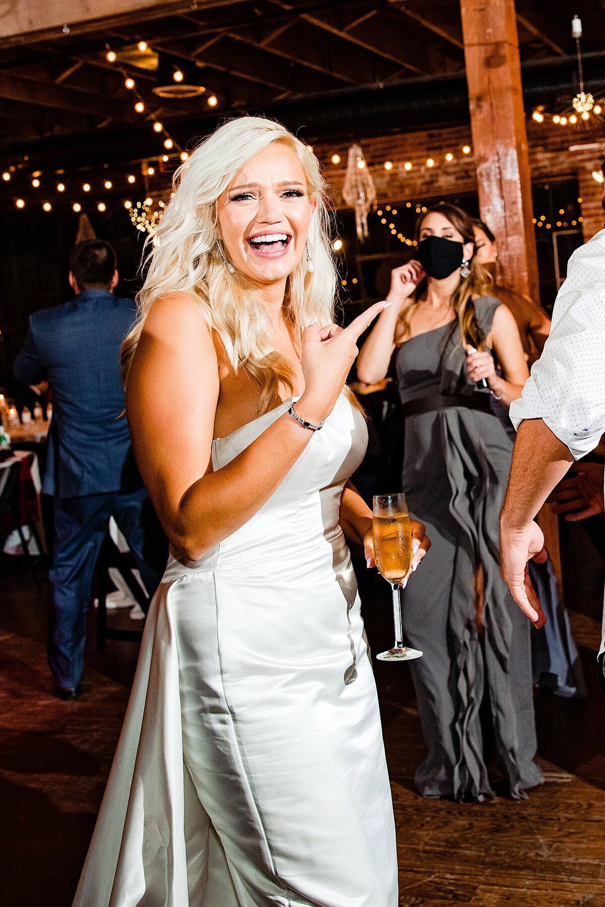 Bride laughing candidly on the dance floor holding a glass of wine